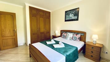 Une chambre à coucher avec un lit, des tables de chevet, une armoire et un tableau encadré au mur.