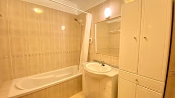 Une salle de bain avec une baignoire, un lavabo et un miroir.