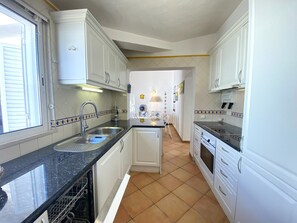 A kitchen with white cabinets, a black countertop, and a tiled floor. - Quinta DA Balaia Charming by Homing (Albufeira)