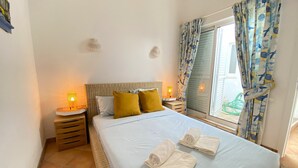 A bedroom with a bed, two bedside lamps, a window with curtains, and a small wall decoration. - Quinta DA Balaia Charming by Homing (Albufeira)