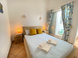 A bedroom with a bed, two bedside lamps, a window with curtains, and a small wall decoration. - Quinta DA Balaia Charming by Homing (Albufeira)