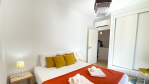 Une chambre d’hôtel avec un lit, une table de chevet, une lampe et une armoire.