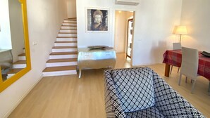 Un salon avec un escalier, un canapé, une table et une lampe.