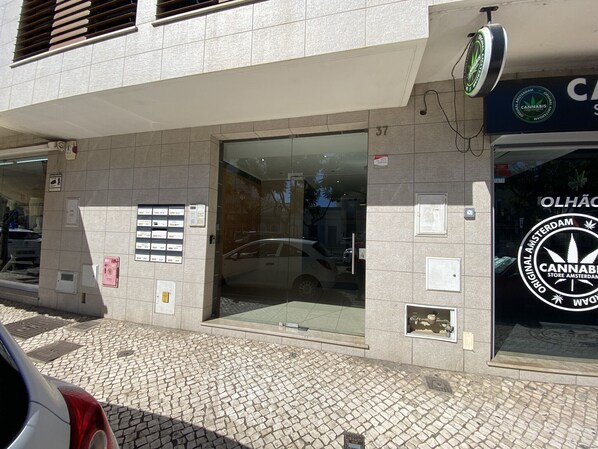 A building with a glass entrance, a sign for a cannabis store, and a tiled pavement. - Olhão Stylish by Homing (Olhao)