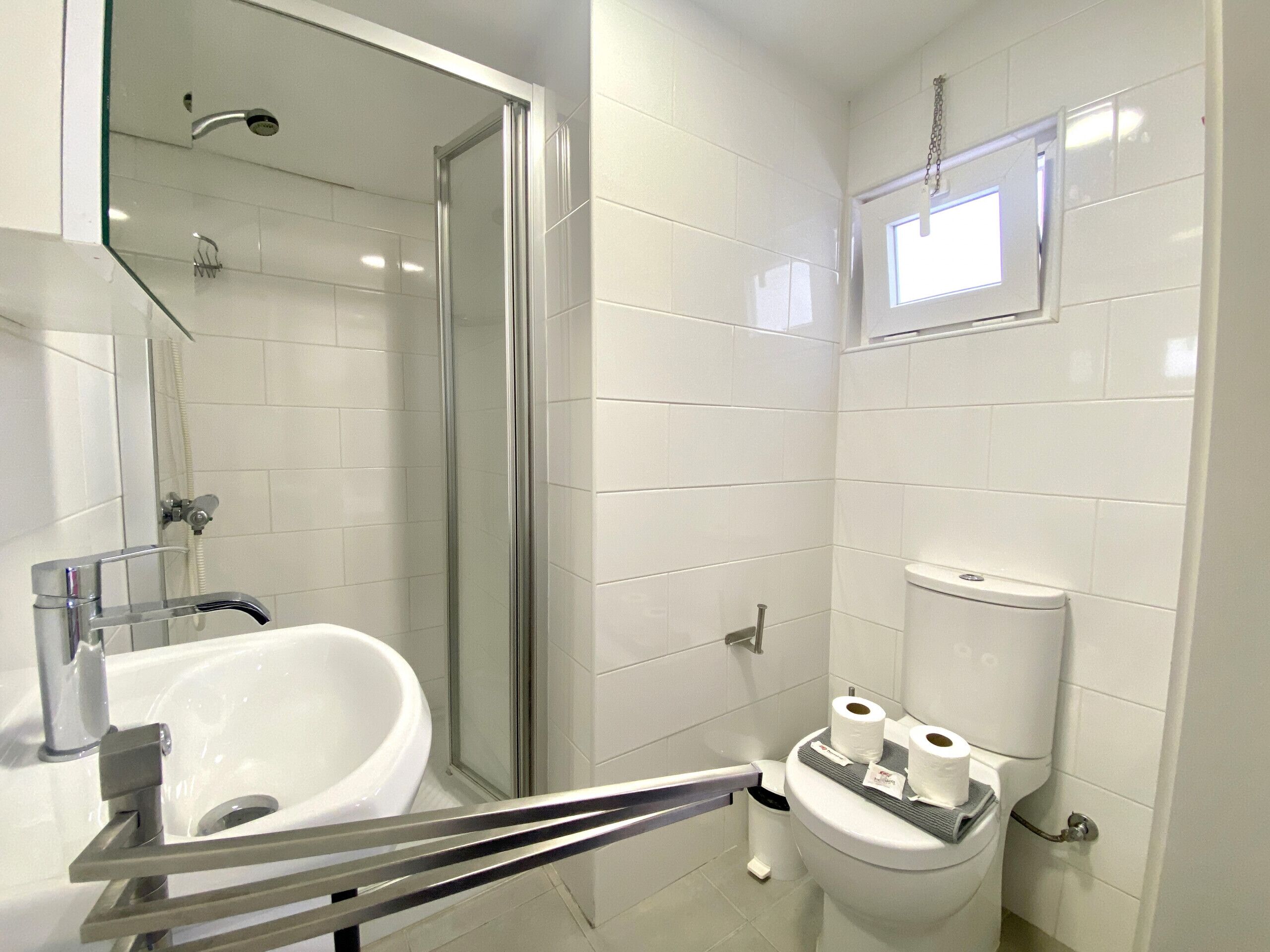 A modern bathroom with a glass shower enclosure, a white sink, and a toilet with toilet paper and a bidet.