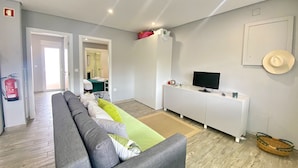 Un salon moderne avec un canapé gris, un téléviseur à écran plat et un meuble blanc.
