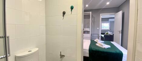 A bathroom with a toilet, two rolls of toilet paper, and a shower area.