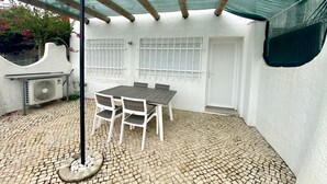 Une terrasse avec une table et des chaises, un ventilateur de plafond et un chauffe-eau.