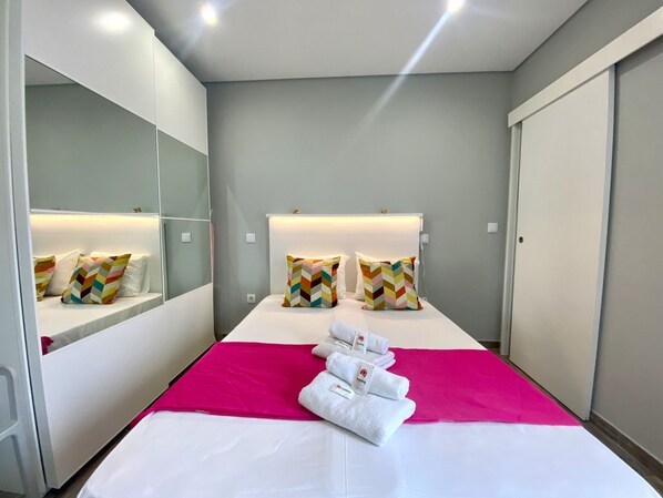 Una habitación de hotel con cama, un espejo grande y un armario.