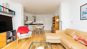 Ein modernes Wohnzimmer mit Sofa, Couchtisch, Fernseher und Bücherregal.