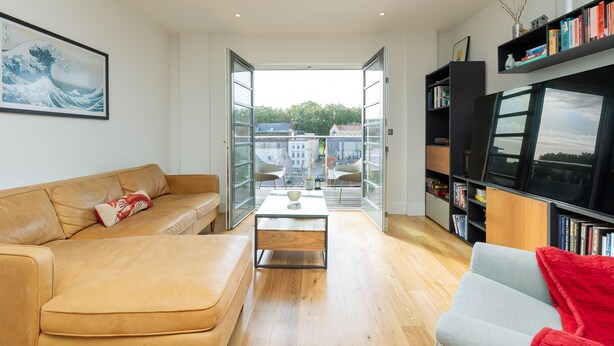 Ein modernes Wohnzimmer mit einer Ledersofa, einem Glastisch und einem Bücherregal.