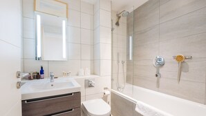 Ein modernes Badezimmer mit einem großen Spiegel, einem Waschbecken, einer Toilette und einer Badewanne.