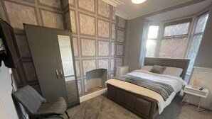 Un dormitorio con una cama grande, un armario, una silla y una mesita de noche.