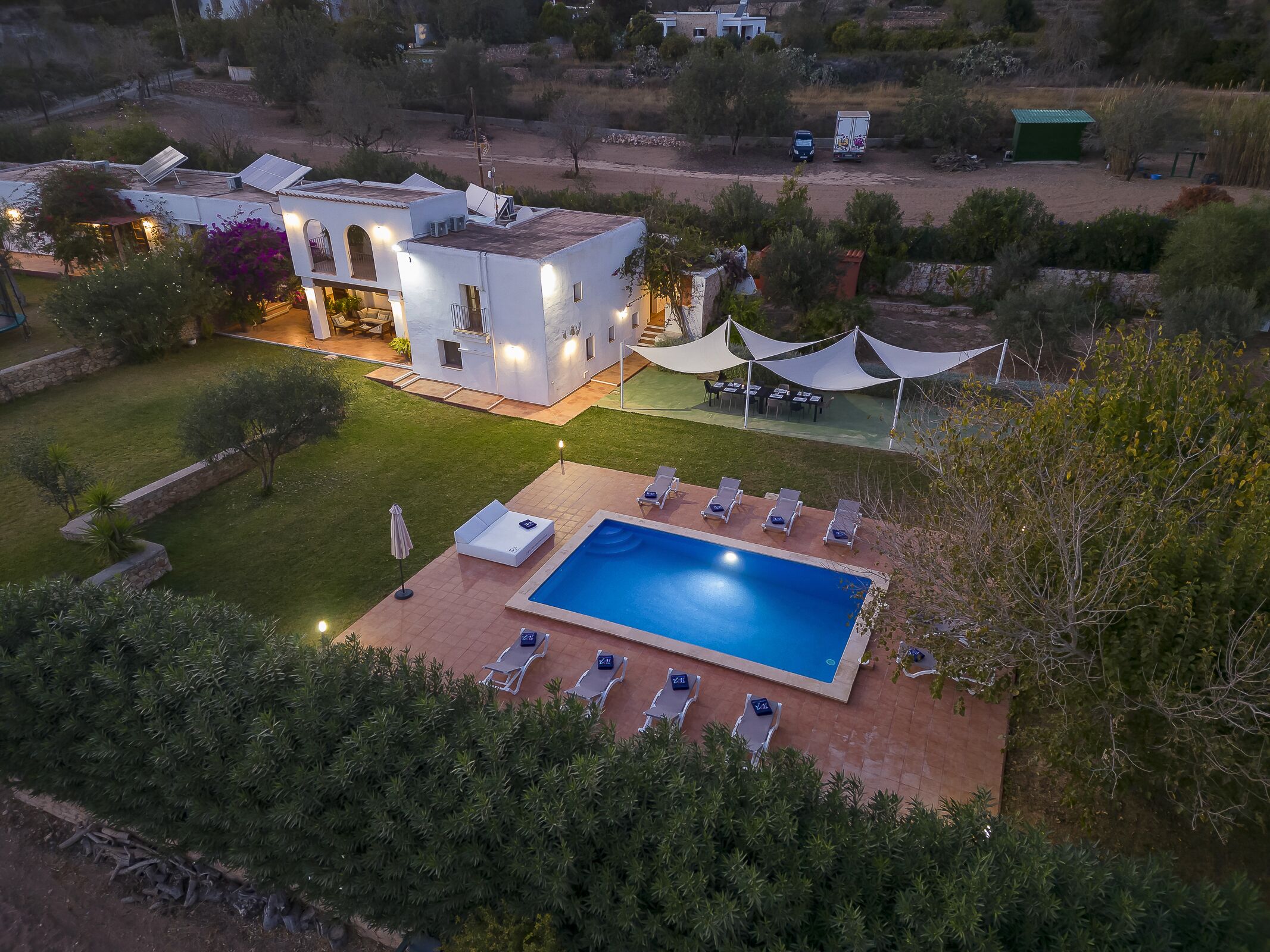 Vista aérea de una casa moderna con piscina, paneles solares y un patio con sillones de descanso.