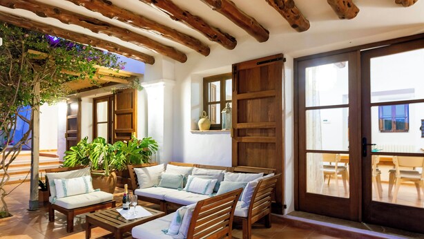 Un área de estar al aire libre acogedora con mobiliario de madera y plantas en macetas.