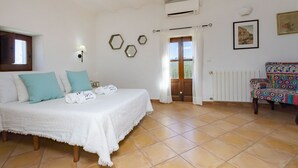 Un dormitorio con una cama, una silla, un ventanal y un equipo de aire acondicionado.