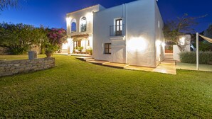 Una casa moderna con un césped cuidado, un muro de piedra y una escalera que lleva a la entrada.
