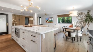 Eine moderne Küche mit einer Marmorinsel, Holzschränken und einem Essbereich mit Tisch und Stühlen.