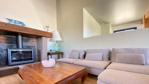 Un salon moderne avec une cheminée, un ensemble de canapés, une table basse en bois et une lampe.