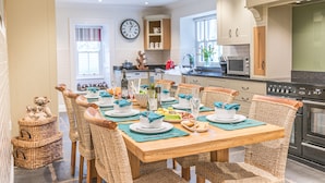 A dining area with a wooden table set for six, surrounded by wicker chairs.