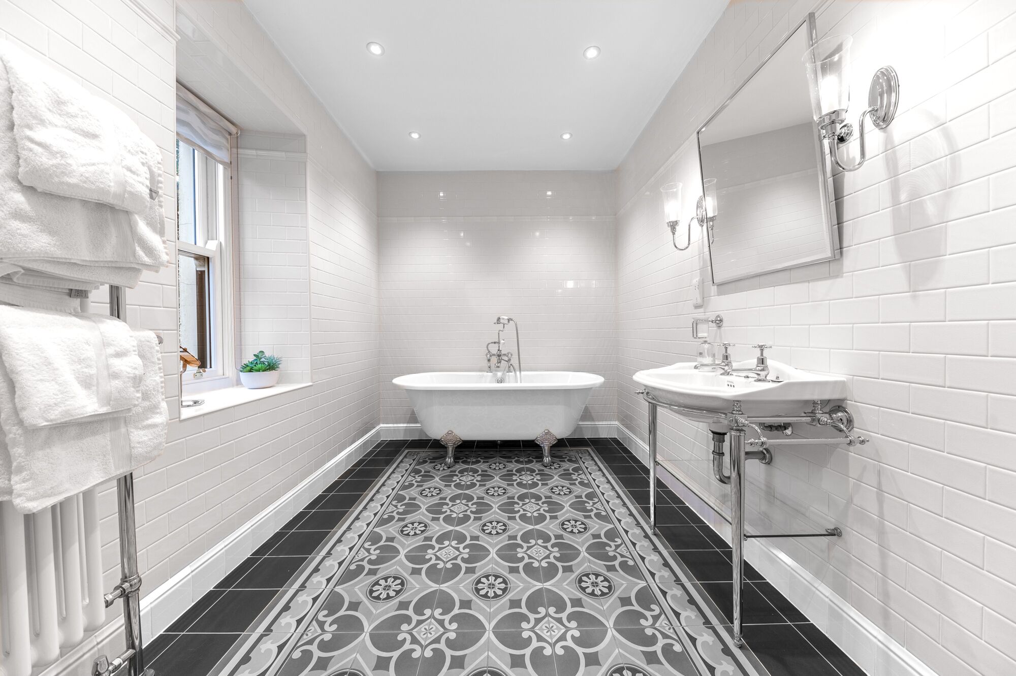 Une salle de bain moderne avec une baignoire sur pieds, un meuble-lavabo et un grand miroir.