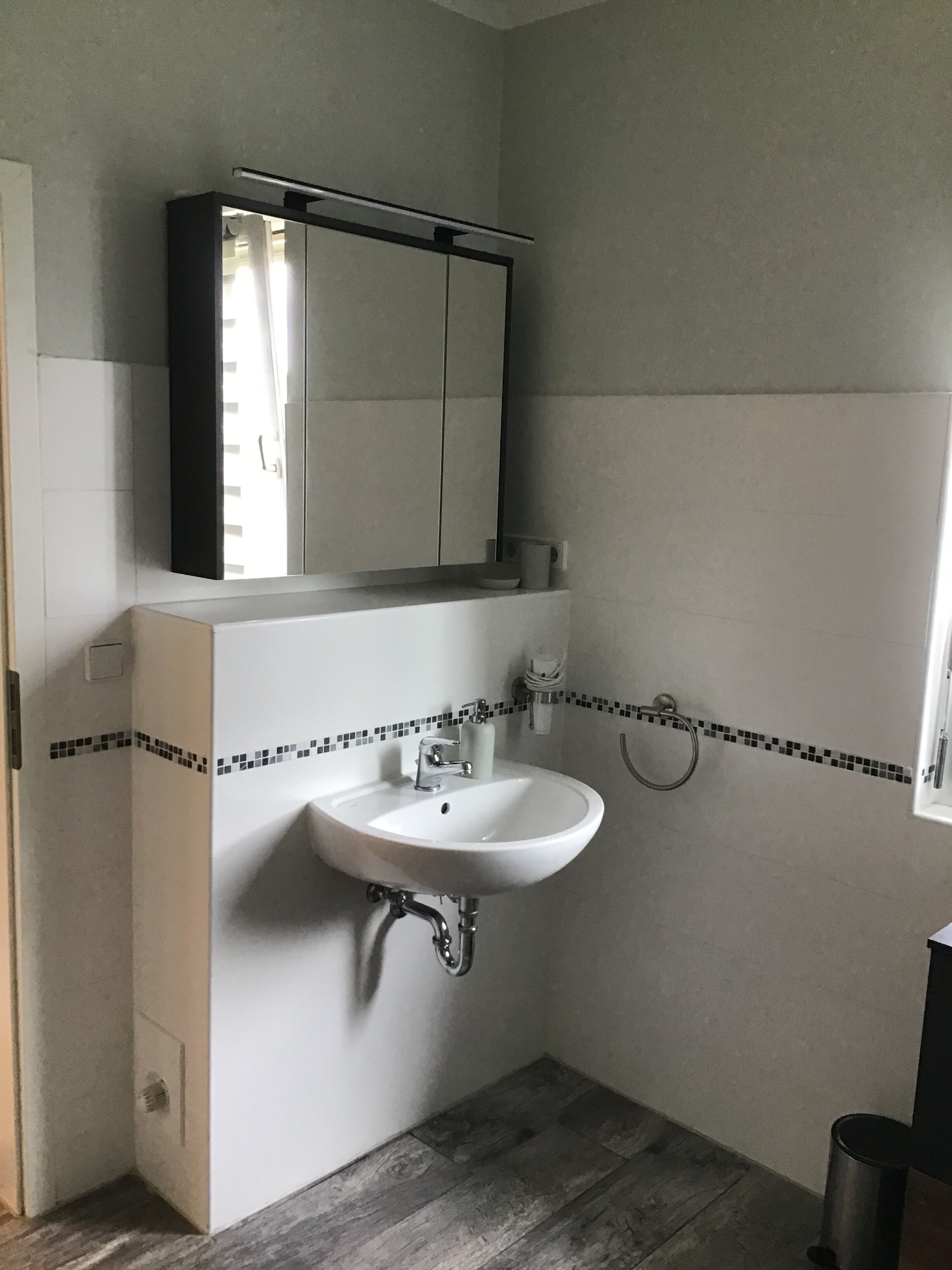 Une salle de bain avec un lavabo blanc, un miroir et une douche.