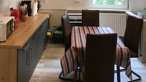 Et kompakt køkken med spiseplads, indbygget ovn og et vindue med udsigt over grønne områder.