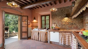 Una cocina rústica con pared de piedra, vigas de madera y horno empotrado.