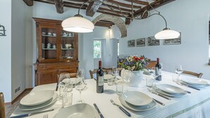 Une salle à manger avec une longue table dressée pour le repas, des meubles en bois et une arche en briques.