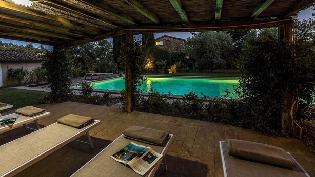 Une terrasse extérieure avec des chaises longues et une piscine.