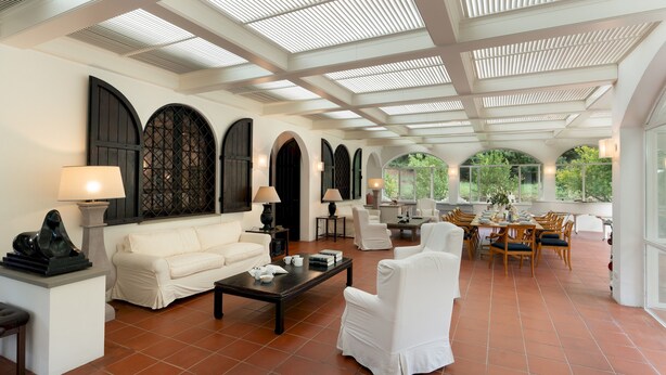 A spacious living area with a high ceiling, large windows, and a dining area with wooden furniture. - Villa Manganelli 12, Emma Villas (Camaiore)