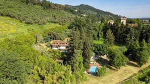 A hillside property with a large house surrounded by dense trees, a small pool, and a tower structure. - Villa Manganelli 12, Emma Villas (Camaiore)