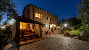Une maison en briques avec une allée pavée, une entrée couverte et un éclairage extérieur.