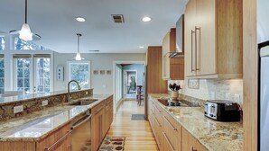A kitchen with wooden cabinets, granite countertops, a built-in toaster, and a view through the windows.