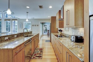 A kitchen with wooden cabinets, granite countertops, a built-in toaster, and a view through the windows.