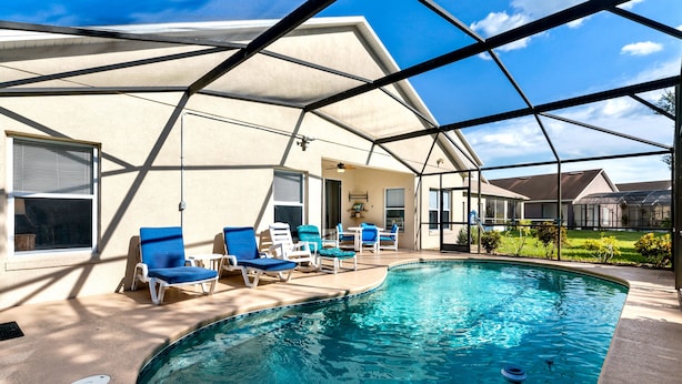 A swimming pool with blue chairs and a covered area. - Aster Cove (Kissimmee)