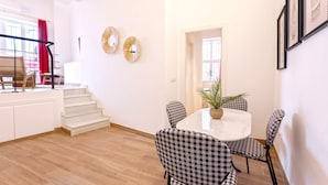 A dining area with a round table, checkered chairs, and a potted plant.