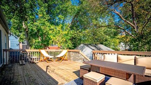 A wooden deck with outdoor furniture, including two chairs and a table. - Theater - Firepit & BBQ - Life Size Games (Minneapolis)