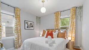 A bedroom with a bed, a bedside table, a lamp, and a framed picture on the wall. - Theater - Firepit & BBQ - Life Size Games (Minneapolis)
