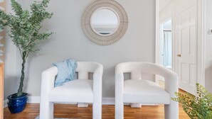 A room with two white chairs, a round mirror, and a potted plant. - Theater - Firepit & BBQ - Life Size Games (Minneapolis)
