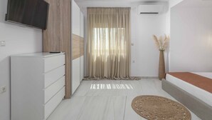 Een moderne slaapkamer met een bed, nachtkastje en een aan de muur bevestigde televisie.