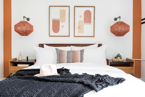 A neatly arranged bedroom with a large bed, two bedside tables, a headboard, and two wall-mounted lamps.