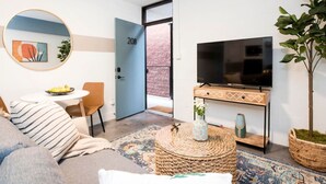 A modern living room with a sofa, a round coffee table, a TV on a wooden console, and a door marked with the number 208. - Midtown Jewel – Walk Ponce City Market & BeltLine (Atlanta)