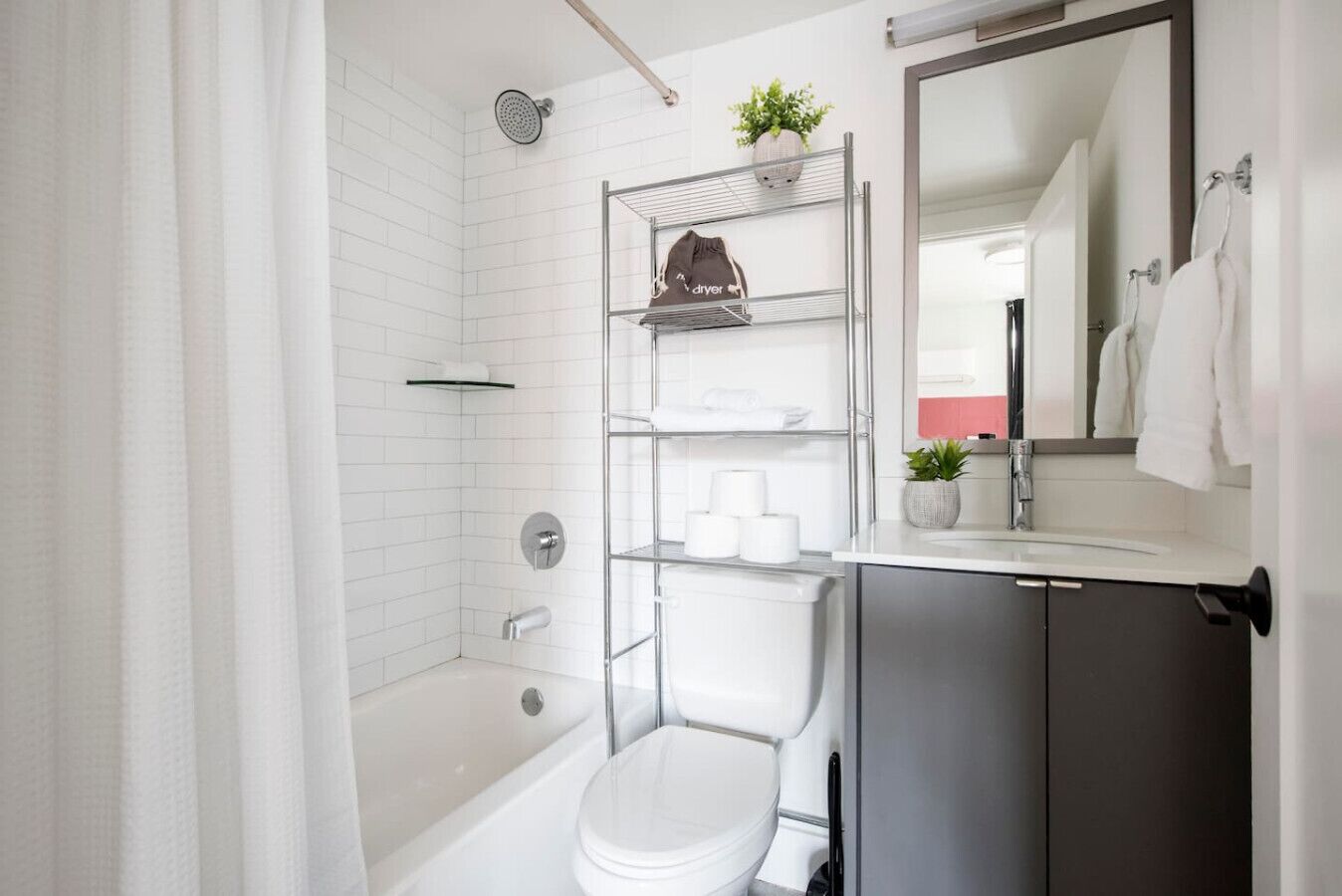 A modern bathroom with a bathtub, toilet, and a shelf with toiletries.