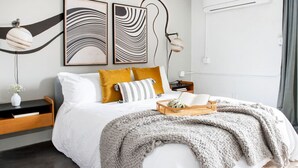 A modern bedroom with a bed, a bedside table, a lamp, and abstract wall art. - The Layla – Walkable Downtown Apartment + Rooftop (Atlanta)