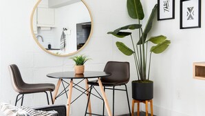 A modern dining area with a round table, two chairs, a potted plant, and a large mirror on the wall. - The Layla – Walkable Downtown Apartment + Rooftop (Atlanta)