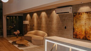 A modern lobby with a sofa, a coffee table, and a decorative vase. - Urban by Hosppedar (João Pessoa)