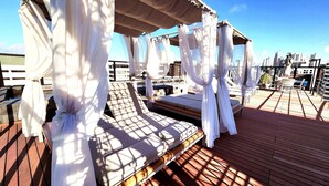 A rooftop terrace with sunbeds and a pergola covered with white fabric. - Urban by Hosppedar (João Pessoa)