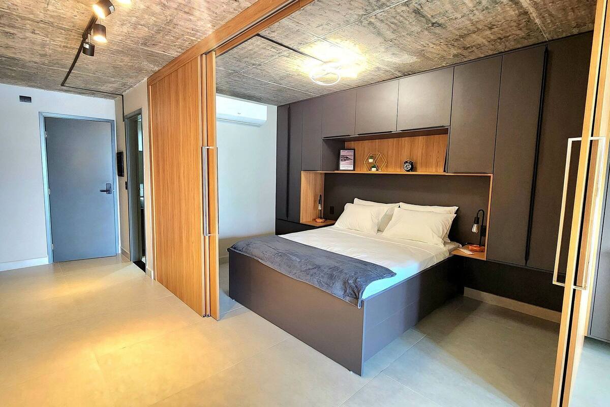 A modern bedroom with a bed, wooden wardrobe, and built-in shelves.