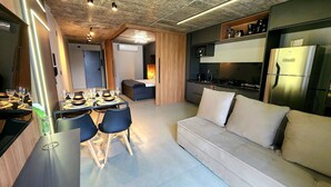 A modern kitchen with a built-in oven, a dining area with a table set for four, and a sofa in the living area. - Urban by Hosppedar (João Pessoa)